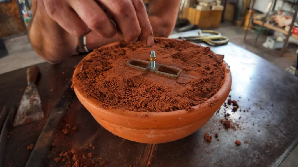 Préparation de l'empreinte négative dans le sable de fonderie à l'aide d'un modèle imprimé en résine 3D.