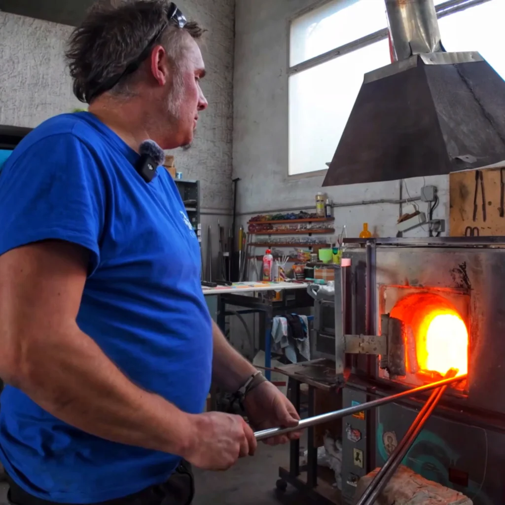 e souffleur de verre Pierrot Dorémus prélève le verre en fusion dans le four principal, maintenu à plus de 1 000 °C, à l'aide d'une canne métallique spécialement conçue pour le travail du verre.